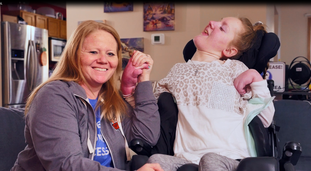 Smiling woman sitting next to adult daughter in wheelchair